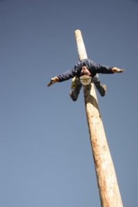 man using safety equipment to keep himself on a telephone pole